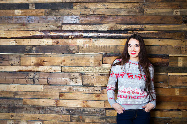 快乐女人穿圣诞节毛衣木墙背景
