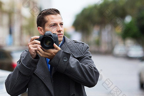 体贴的男摄影师在街上拿着照相机