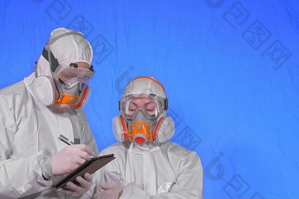 戴口罩的科学家病毒学家用手写笔在平板电脑上书写。戴着医用防护面具的男女。色度键蓝色。