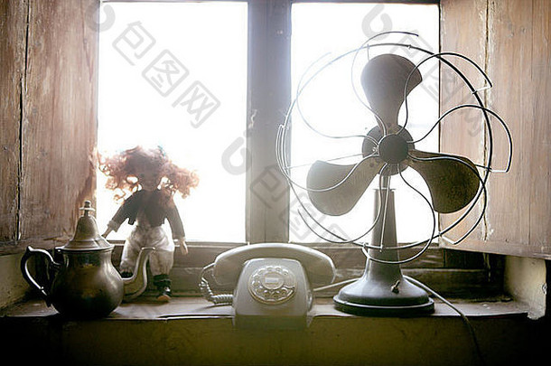 窗户背光处的复古风扇、玩偶和电话