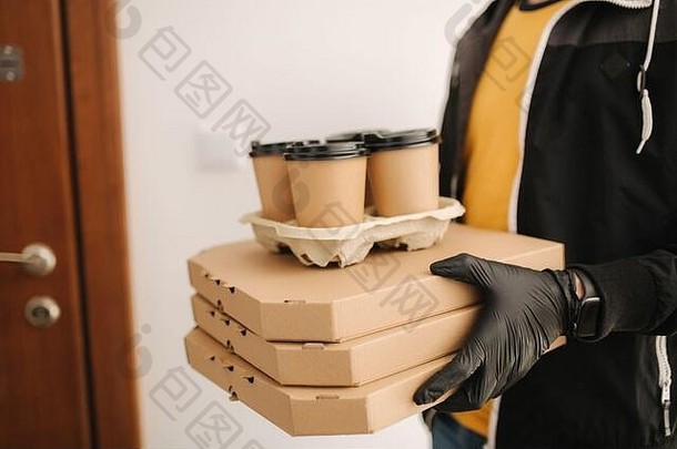 男人拿着树盒子披萨的特写镜头。男子戴口罩和手套向顾客递送食物和咖啡。冠状病毒主题