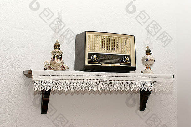 墙上挂着古董收音机，还有两盏古老的传统灯