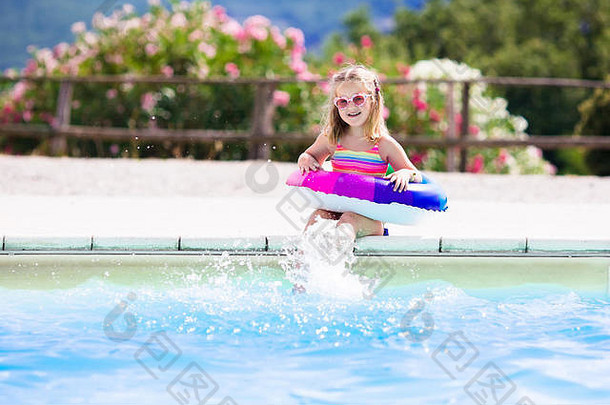 在炎热的<strong>夏日</strong>，快乐的小女孩在室外<strong>游泳</strong>池里玩着五颜六色的充气戒指。孩子们学习<strong>游泳</strong>。儿童水玩具。儿童解放军