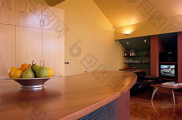 开放式厨房，马赛克瓷砖半岛单元上有一碗水果，木质台面