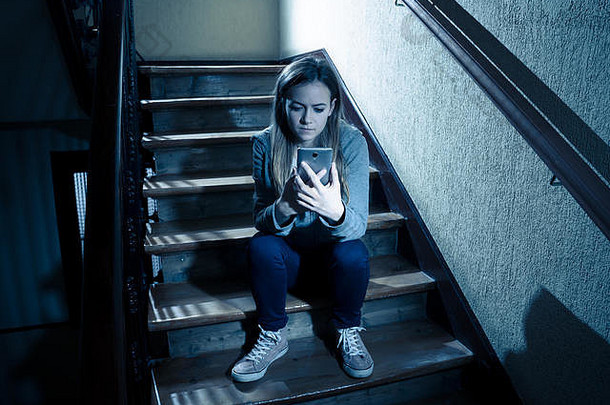 悲伤沮丧的年轻女孩，手机网络<strong>欺凌</strong>的受害者，坐在楼梯上，感到孤独、不快乐、绝望和被虐待。欺负
