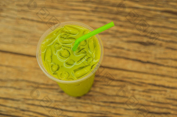 绿色茶拿铁冰塑料杯稻草木背景自制的冰火柴拿铁茶牛奶