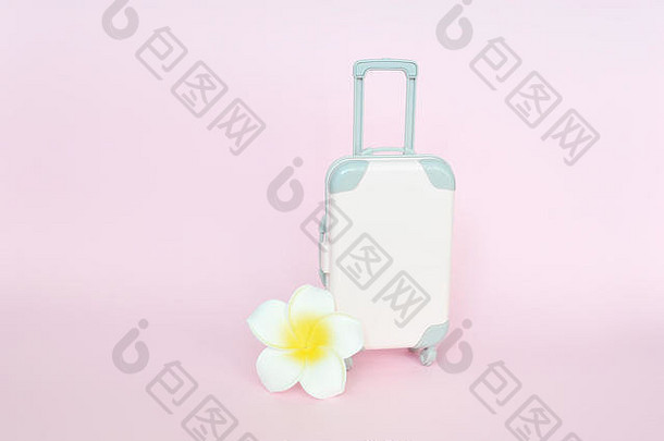 时尚的手提箱和粉色背景上的白色花朵，俯视图中有文字位置。旅游概念
