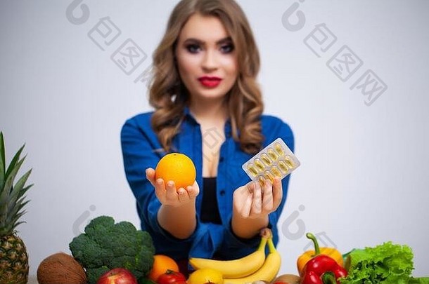 女人表格持有橙色药片水果蔬菜背景