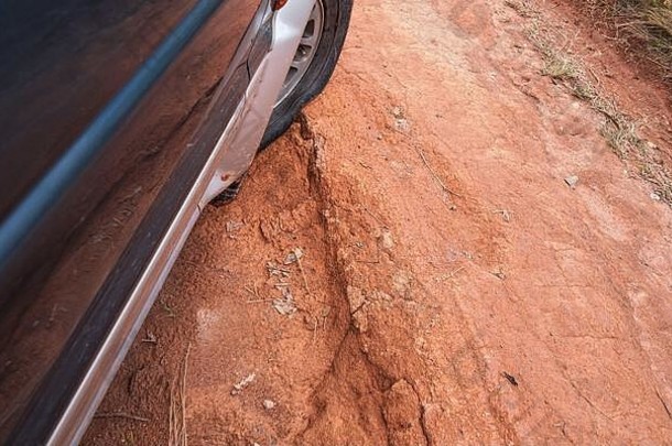在布满红色灰尘的乡间道路上驾驶四轮驱动车辆，道路上有大洞，轮胎上有细节，在崎岖的地形上行驶时有低压。路上的道路状况很差