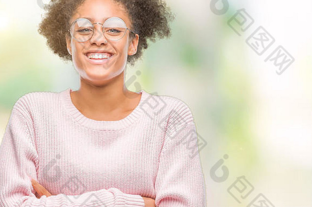 年轻的非裔美国妇女戴着眼镜，在孤立的背景下微笑着双臂看着摄像机。积极的人。