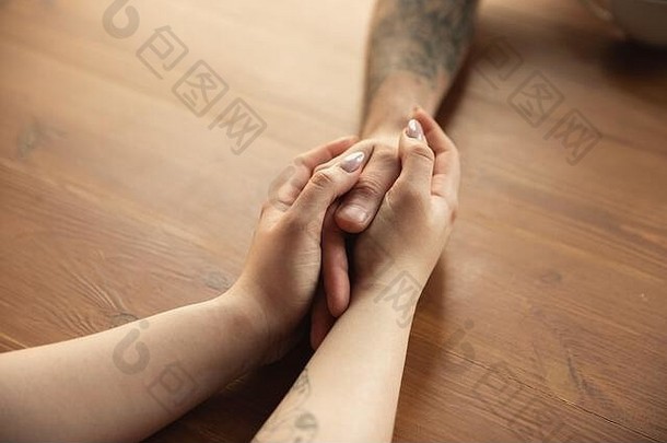 一对相爱的白人夫妇手牵手在木制背景上近距离拍摄。浪漫的，爱情的，关系的，温柔的。支持和帮助之手，家庭，温暖。团结、感觉和情感。