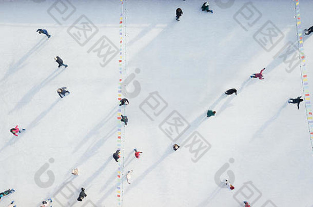 冬季阳光明媚的日子里，一架无人驾驶飞机在露天溜冰场上与人们一起鸟瞰。