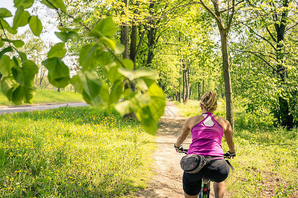 夏日，在城市公园骑山地车的女人。激发和激发户外活动的概念。骑自行车的女孩微笑着骑着自行车