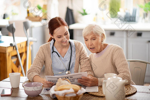 护理人员为退休妇女阅读晨报