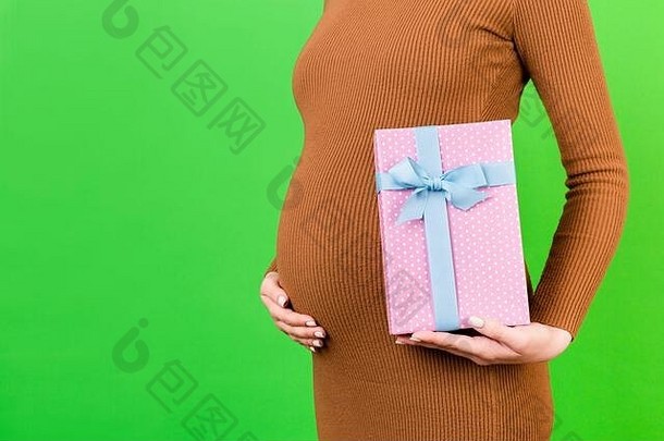 裁剪图像怀孕了女人棕色（的）衣服持有粉红色的发现了礼物盒子绿色背景等待婴儿女孩复制空间