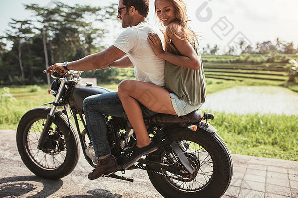 户外拍摄快乐年轻的夫妇享受摩托车骑国家路女人坐着回来男人。开车摩托车用力推