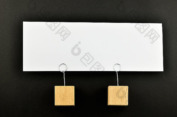 一张大白纸便笺和两个木托放在一起，分别放在黑纸背景上，用于演示