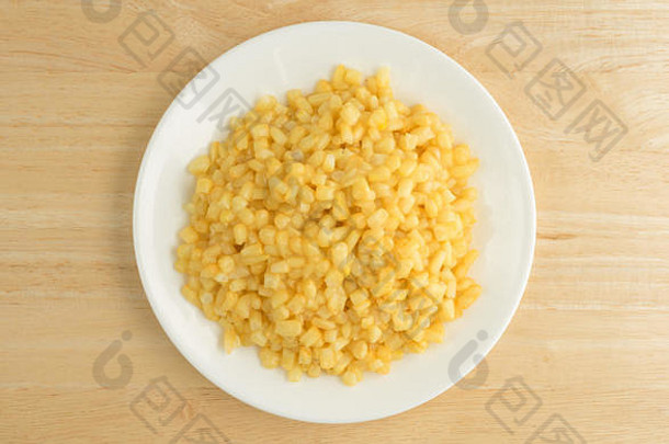 在木桌上的<strong>白</strong>色盘子上放着带黄油酱的shoepeg<strong>白玉米</strong>的俯视图。