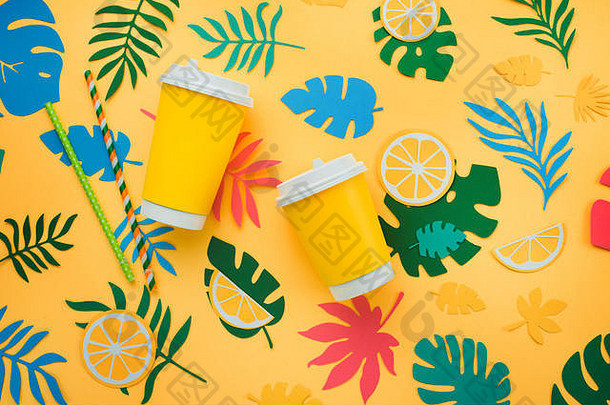 <strong>柠檬水</strong>纸杯采用热带风格，橙子、树叶和水果图案，明亮的黄色背景。阳光明媚的<strong>夏日</strong>，五颜六色的公寓铺着剪纸。
