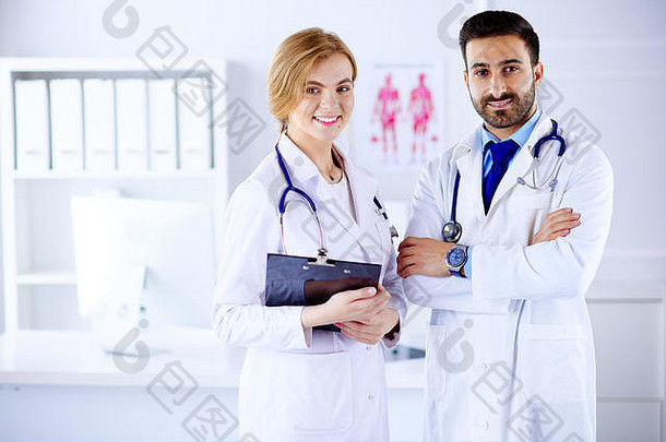 两位医生都站在一间咨询室里，手里拿着病人的病历