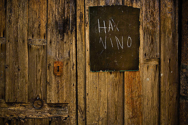 西班牙卡塞雷斯市圣马丁·德·特雷维乔村一扇木门上挂着黑色石板写的广告