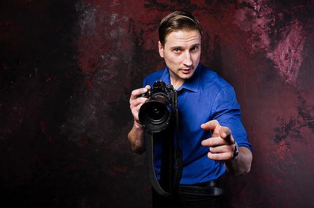 时尚专业摄影师的摄影棚肖像，带相机，穿蓝色衬衫和领带。