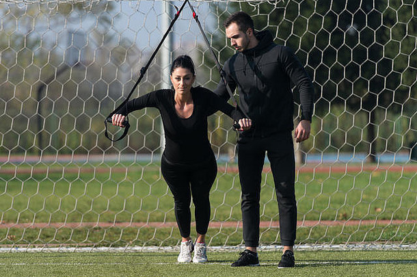 年轻的夫妇参考trx健身肩带城市公园区域培训锻炼耐力健康的生活方式概念户外