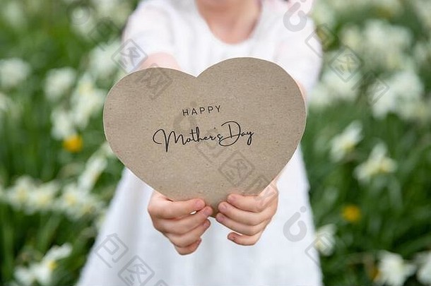 快乐母亲的一天写心形的卡举行女孩花草背景