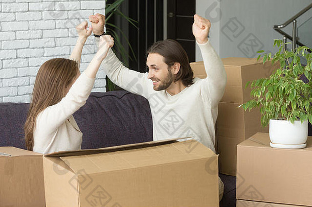 带着盒子的夫妇举手庆祝搬进新家