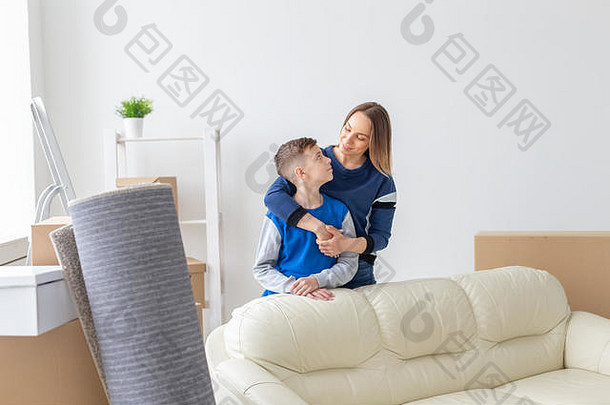积极的微笑单妈妈。迷人的儿子摆姿势站明亮的舒适的公寓概念移动抵押贷款