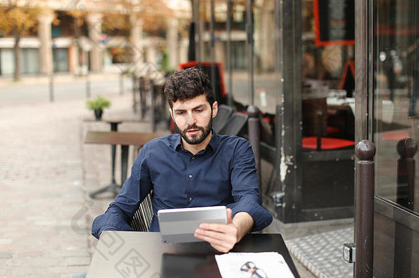 一名<strong>心怀</strong>不满的男子在街边咖啡馆用平板电脑玩网络游戏。