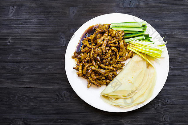 中式菜肴-顶视图白色盘子，带酱油炒猪肉片，配大葱、新鲜黄瓜和煎饼（北京猪肉）