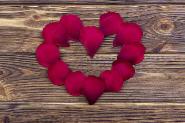 红色的玫瑰花瓣形成心形状环棕色（的）木背景