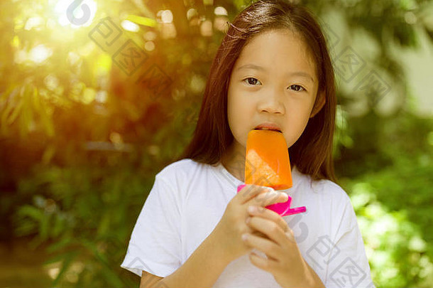快乐的亚洲孩子在炎热的夏天吃冰棒冰淇淋。