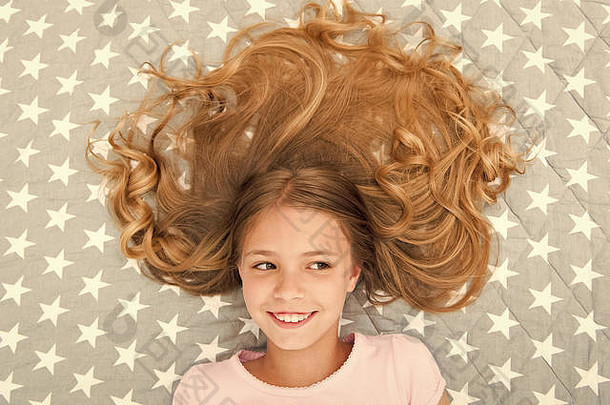 孩子卷曲的发型放松护发素面具有机石油头发闪亮的健康的令人惊异的头发提示头发卷曲的早....女孩孩子长头发躺床上前视图