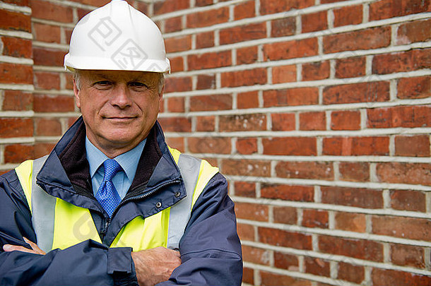 维护工程师在砖墙背景下的头肩视图。