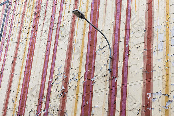 带街灯的公寓楼破旧的墙壁上摇摇欲坠、剥落的旧油漆。这幅画开始褪色，颜色松散。