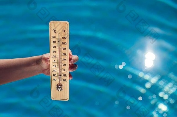 女人持有温度计蓝色的池背景热天气夏天概念