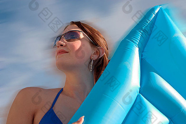 女孩向着天空持有海滩inflateable床上
