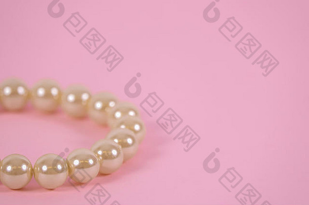 粉红色背景上的美丽珍珠手镯。为自己的文本提供空白空间。