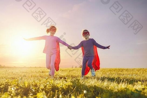 两个小孩正在扮演超级<strong>英雄</strong>。孩子们在<strong>日</strong>落的天空中。女孩权力观