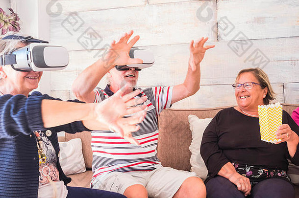 三名高级工程师在家里尝试虚拟现实技术。坐在沙发上，笑着等待退休后的新体验。友谊观