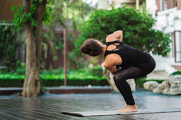 在热带岛屿的木甲板上，一位有着东方容貌的年轻女子独自练习瑜伽。运动、健身、健康的生活方式理念。