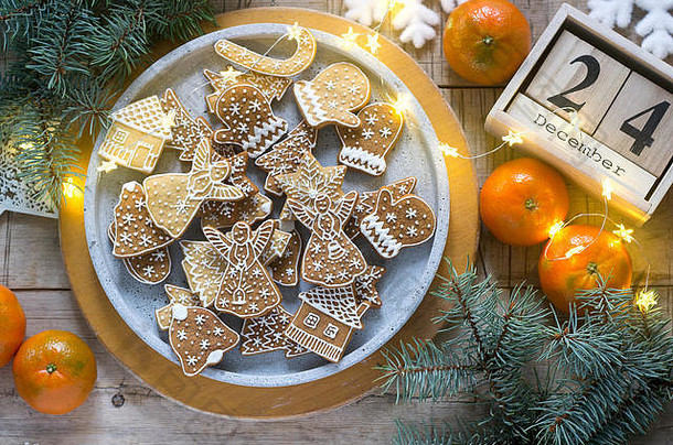姜饼饼干放在混凝土托盘上，背景是冬天的橘子、冷杉枝和花环。