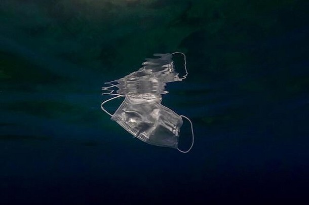 人们把医用面罩扔到海水中。用过的外科口罩漂浮在海底。无用的冠状病毒卫生口罩。感染