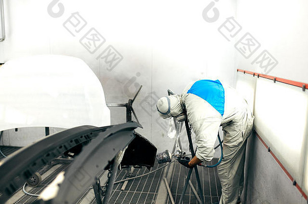 工人在专用车库油漆汽车零件，穿着服装和防护装备