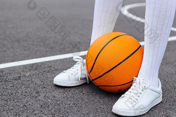 特写沃南穿着白色运动鞋和whote长袜的脚，在篮球场上踢球。