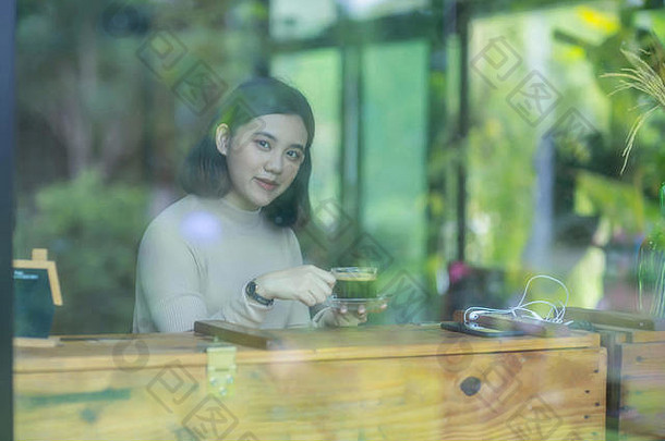 年轻的亚洲女孩在咖啡馆的咖啡厅里喝咖啡