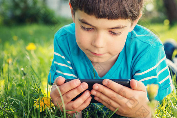 夏天躺在草地上的孩子用手机