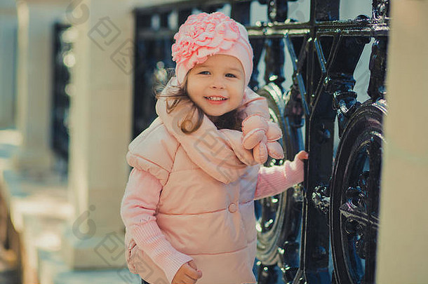多莉戴着小指夹克，戴着温暖的冬帽，穿着时尚的衣服，在秋春公园摆着姿势。周末快乐地微笑着